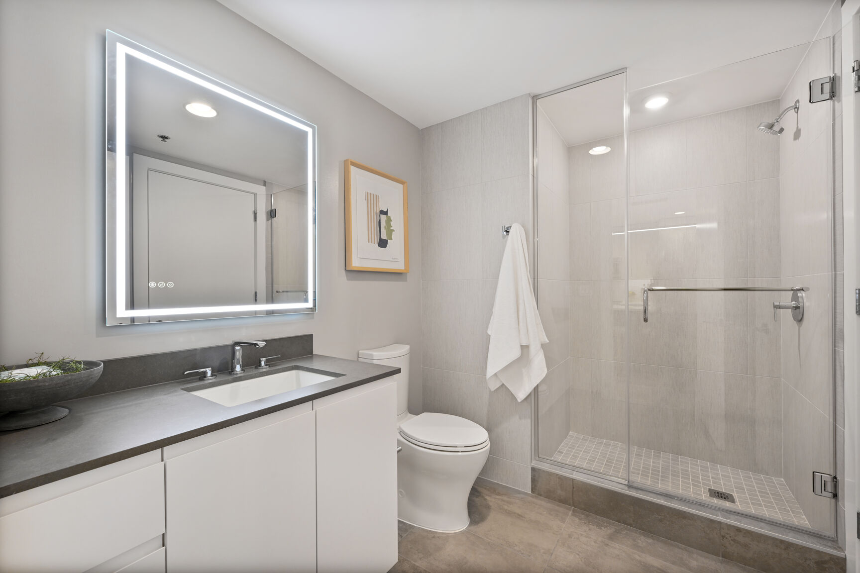 High Rise Apartments Near Safeway in Mount Vernon Triangle, Washington, D.C. - Claret - Bathroom with a Frameless Glass Shower, a Backlit Mirror, and Tiled Flooring