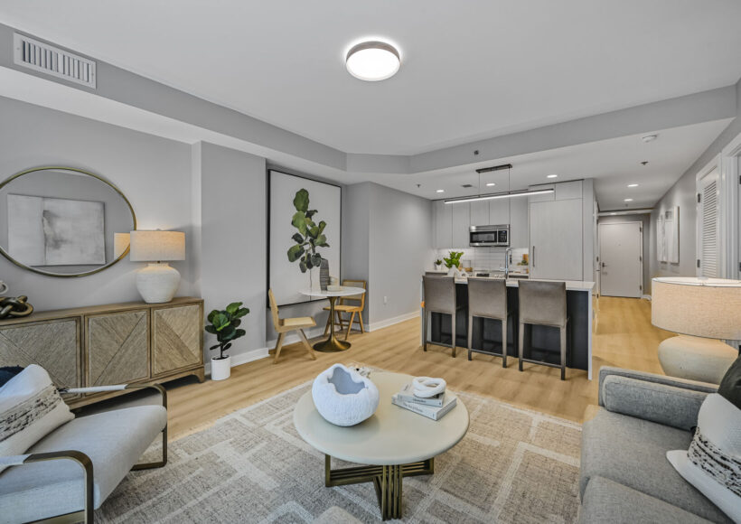Mount Vernon Triangle, Washington, DC, Luxury Apartments Near Safeway - Claret - Living Room With Luxury Plank Flooring, Couch, Armchair, Round Coffee Table, Side Table, Lamps, And Large Windows.